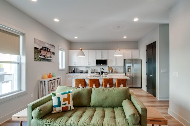 1122 Harmony Way, Nashville, TN 37207 - kitchen featuring backsplash, white cabinetry, appliances with stainless steel finishes, a center island with sink, and light wood-style floors