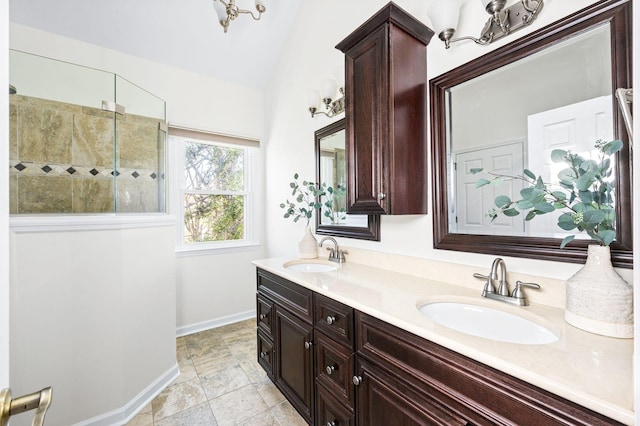 bathroom with baseboards, a sink, vaulted ceiling, and walk in shower