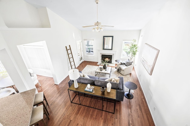 living area with baseboards, wood finished floors, a high end fireplace, and a ceiling fan