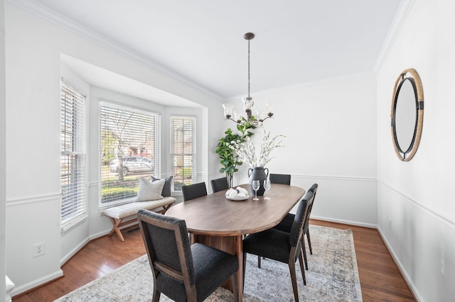 dining space with a notable chandelier, crown molding, and wood finished floors