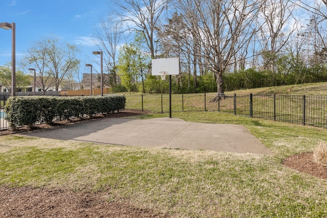 view of basketball court featuring a lawn, community basketball court, and fence