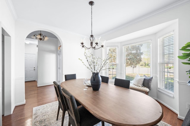 dining room with crown molding, an inviting chandelier, baseboards, arched walkways, and wood finished floors