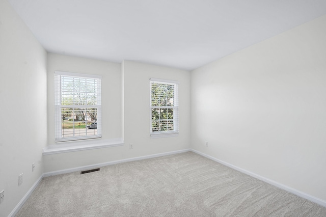 empty room featuring baseboards, visible vents, and carpet floors