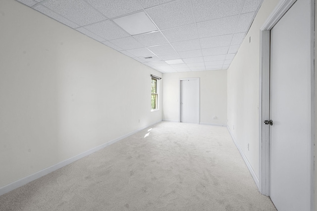 unfurnished room featuring a drop ceiling, carpet, and baseboards