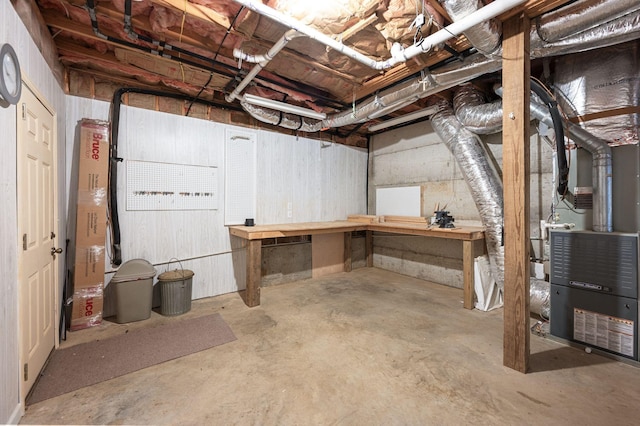 unfinished basement featuring heating unit and a workshop area