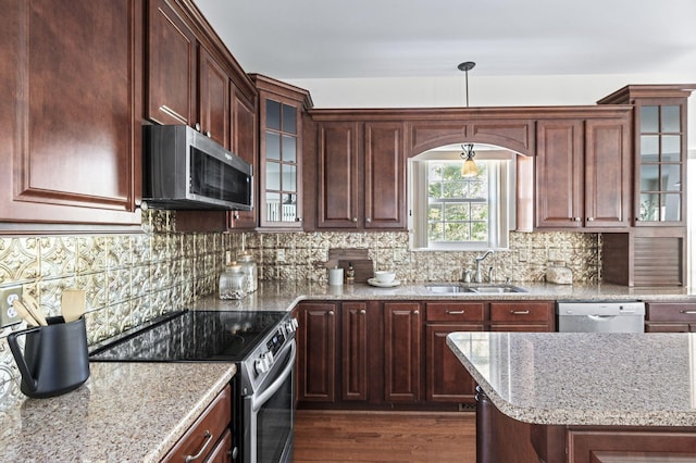 kitchen with light stone counters, a sink, tasteful backsplash, appliances with stainless steel finishes, and dark wood finished floors