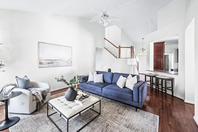 living room featuring high vaulted ceiling, baseboards, stairs, wood finished floors, and a ceiling fan