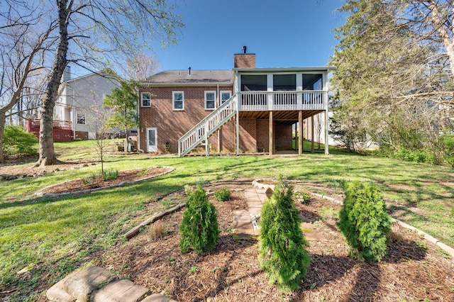 back of property with a sunroom, a chimney, stairway, and a yard