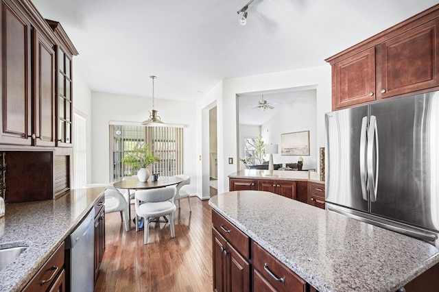 kitchen featuring ceiling fan, appliances with stainless steel finishes, decorative light fixtures, dark wood-style floors, and a center island