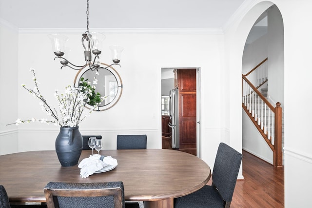 dining area featuring an inviting chandelier, crown molding, stairway, and wood finished floors