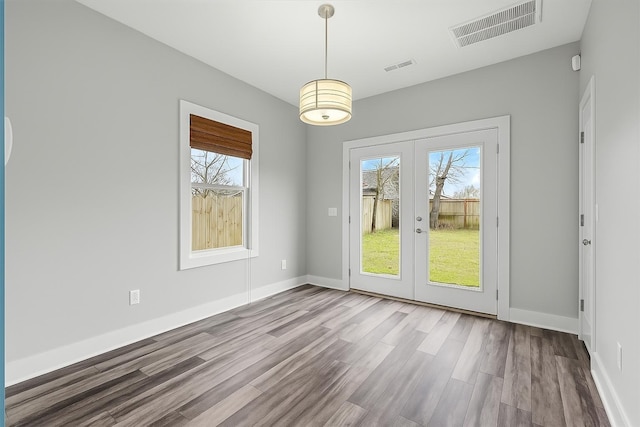 unfurnished room with a wealth of natural light, visible vents, and french doors