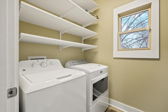 washroom featuring washing machine and clothes dryer, baseboards, and laundry area