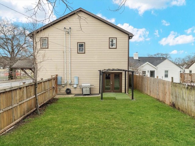 back of house with a fenced backyard, a lawn, and french doors