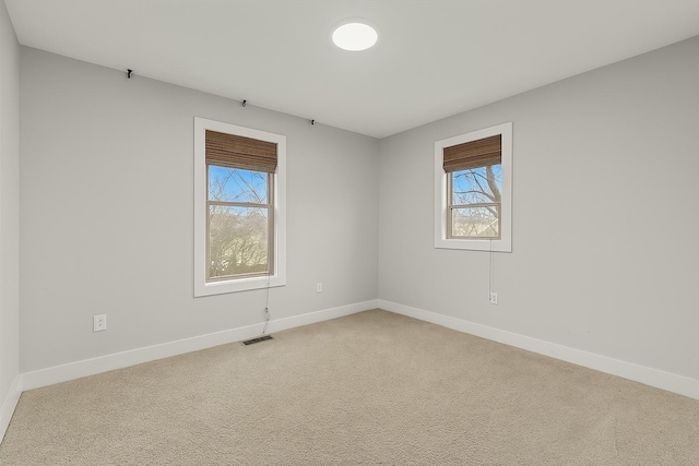 empty room featuring light carpet, baseboards, and visible vents