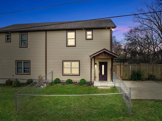 view of front of house with a patio, fence private yard, roof with shingles, and a front lawn