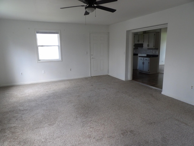 interior space with baseboards, dark colored carpet, and ceiling fan