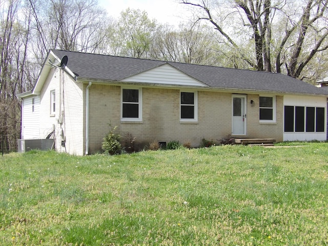ranch-style house featuring entry steps, brick siding, a front lawn, and roof with shingles