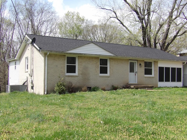 single story home with cooling unit, brick siding, a shingled roof, and a front lawn
