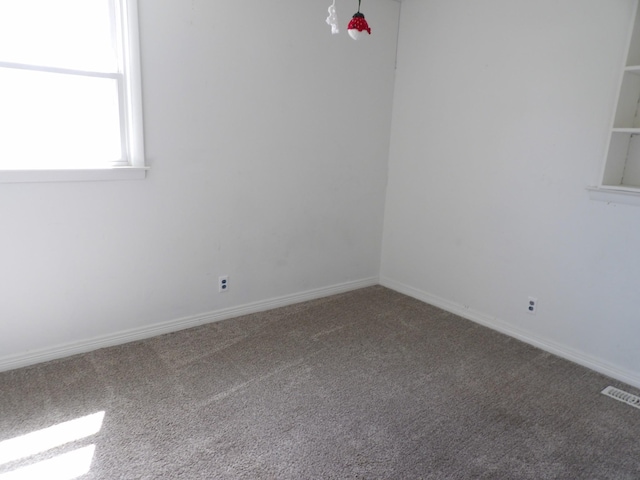 unfurnished room with carpet floors, baseboards, and visible vents