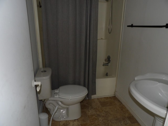 bathroom featuring shower / tub combo, toilet, and a sink