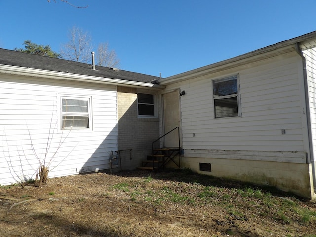 rear view of house with roof with shingles and entry steps