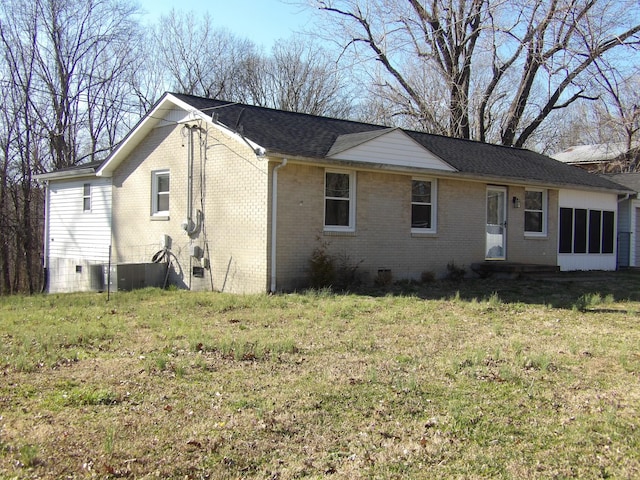 exterior space featuring roof with shingles, brick siding, and a yard