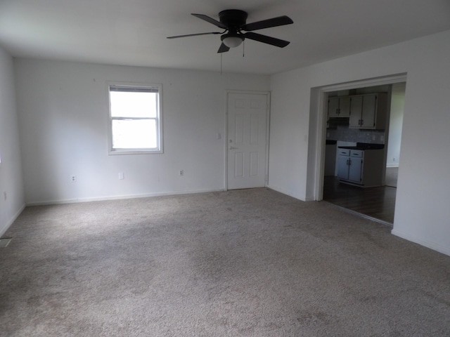 unfurnished room featuring a ceiling fan, carpet floors, and baseboards