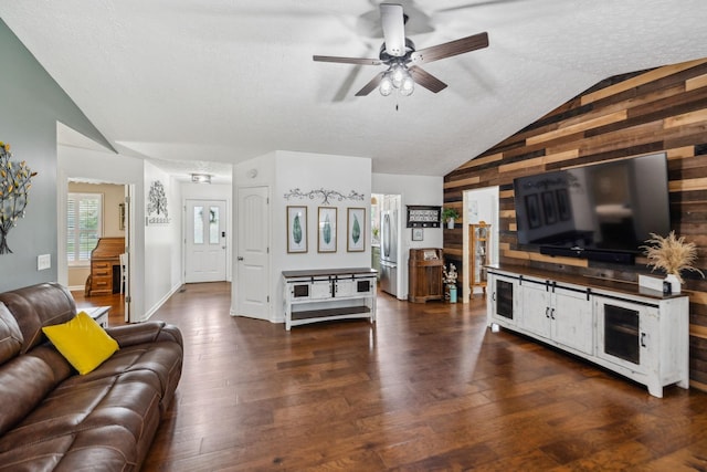 living room featuring dark wood finished floors, lofted ceiling, ceiling fan, and a textured ceiling
