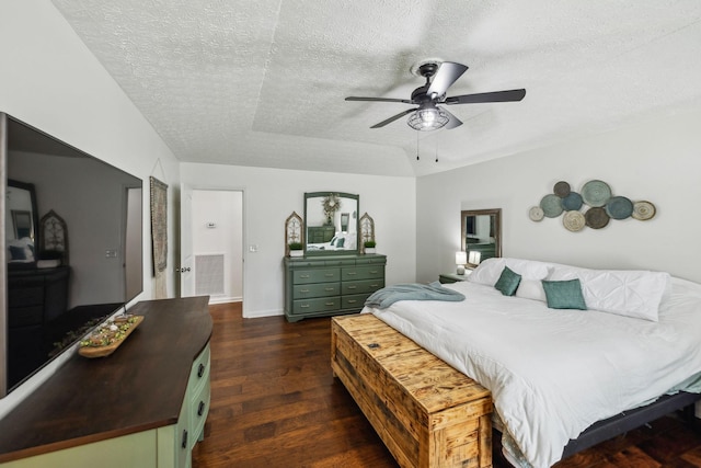 bedroom with dark wood-style flooring, a textured ceiling, baseboards, ceiling fan, and a tray ceiling