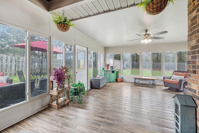 sunroom / solarium featuring lofted ceiling, a deck, wood finished floors, and ceiling fan