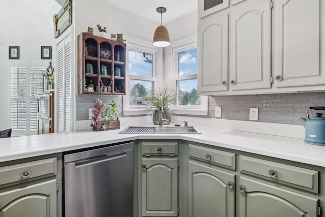 kitchen with light countertops, a sink, tasteful backsplash, and dishwasher