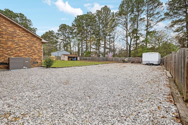 view of yard with an outbuilding, a storage unit, and a fenced backyard