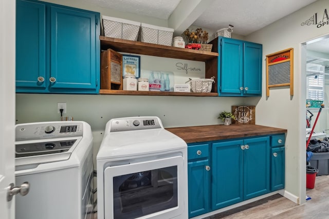 laundry room featuring washing machine and dryer, light wood-style floors, cabinet space, and a textured ceiling