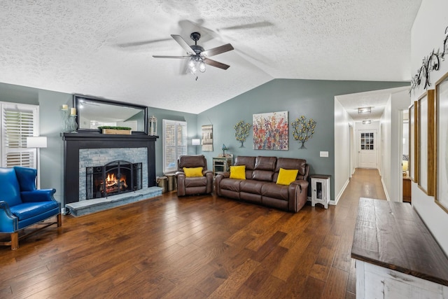 living room featuring a fireplace, a textured ceiling, lofted ceiling, ceiling fan, and hardwood / wood-style floors