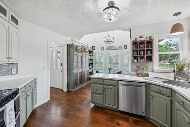 kitchen featuring stainless steel appliances, dark wood finished floors, backsplash, a sink, and a peninsula