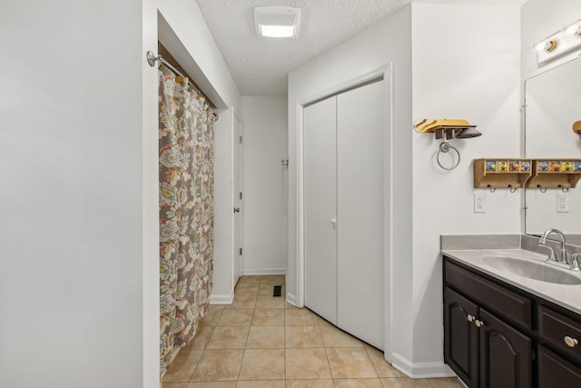full bath with tile patterned floors, vanity, baseboards, and a textured ceiling