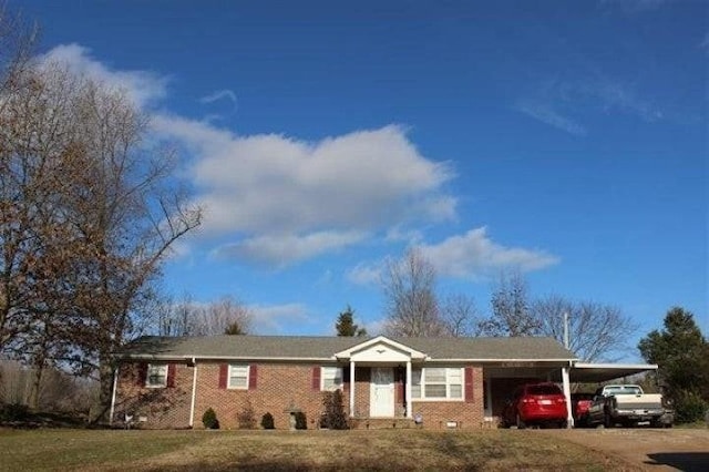 ranch-style home featuring brick siding, an attached carport, driveway, and a front lawn
