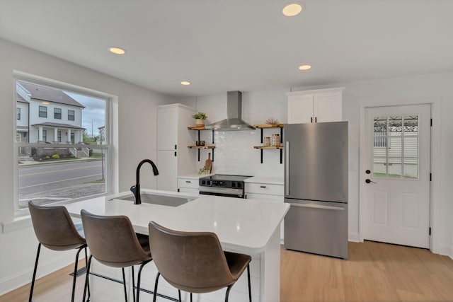 kitchen with a sink, open shelves, range with electric stovetop, wall chimney range hood, and freestanding refrigerator