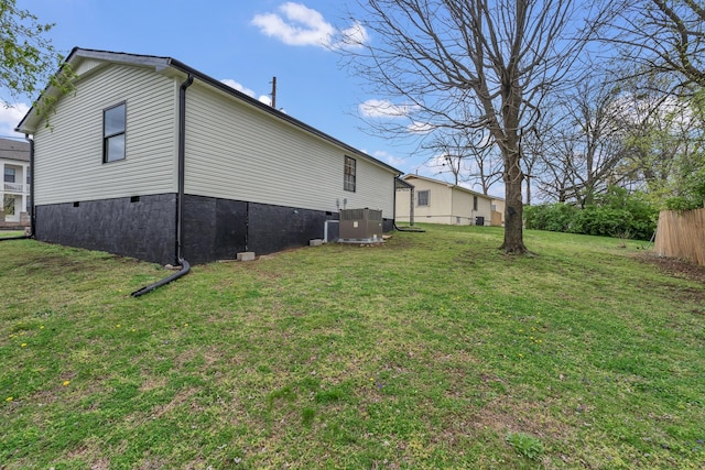 view of side of home with a lawn, cooling unit, and fence