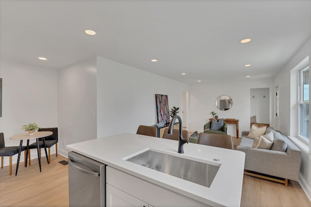 kitchen featuring a sink, dishwasher, light wood-type flooring, white cabinets, and recessed lighting
