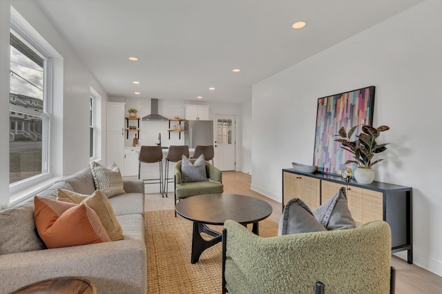 living room featuring baseboards, light wood-style flooring, recessed lighting, and plenty of natural light