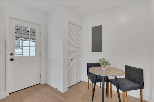 dining area featuring electric panel, baseboards, and light wood-style floors