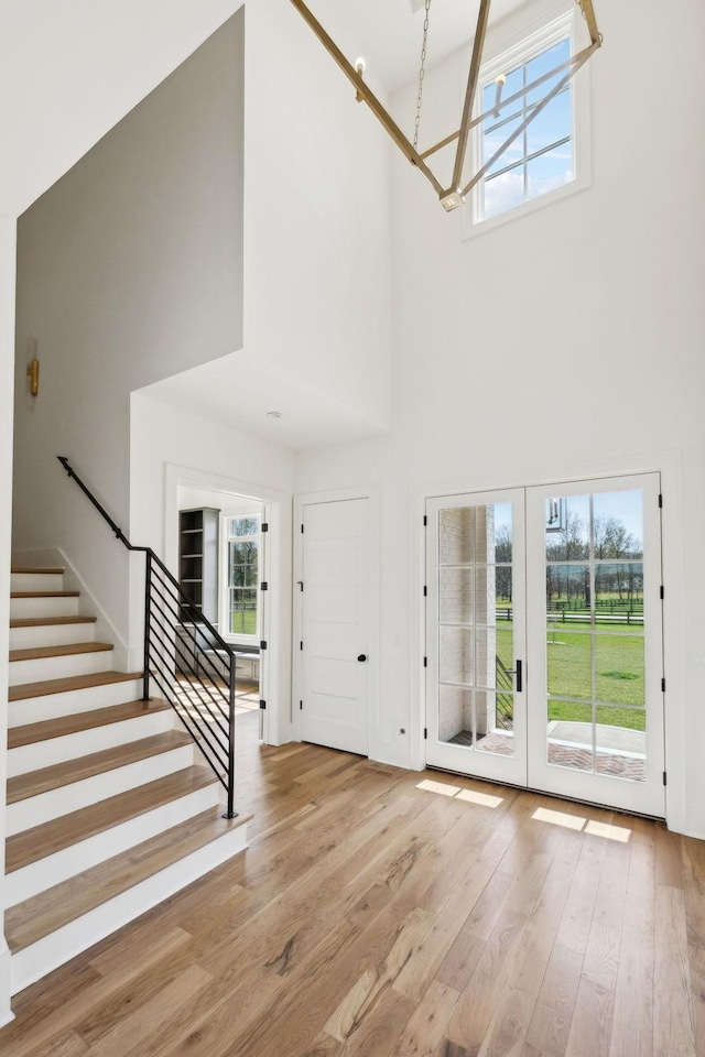 foyer featuring stairs, a towering ceiling, wood finished floors, and a notable chandelier