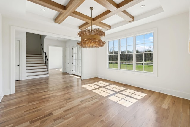empty room featuring coffered ceiling, an inviting chandelier, stairway, and light wood-type flooring