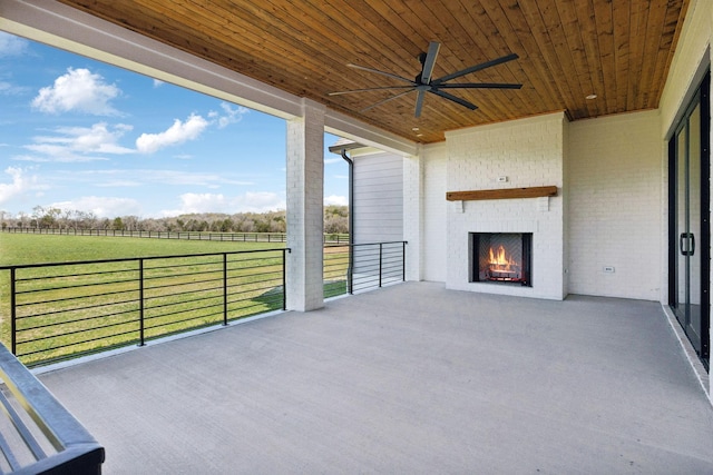 view of patio / terrace with an outdoor brick fireplace, ceiling fan, and a rural view