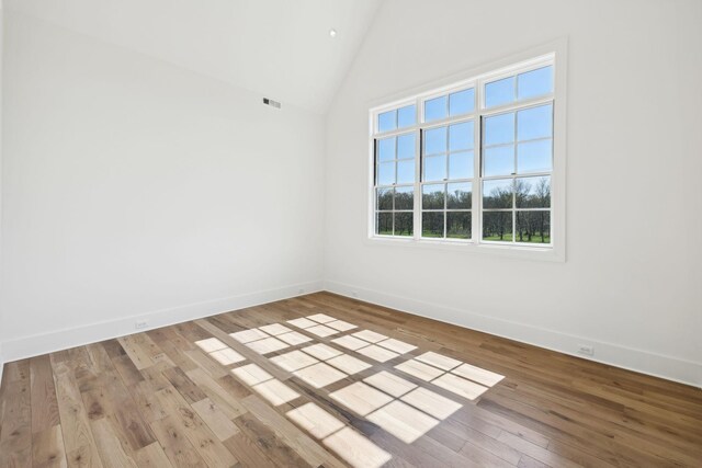 empty room featuring baseboards, visible vents, high vaulted ceiling, and hardwood / wood-style floors
