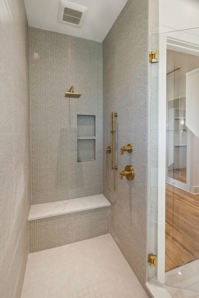 full bath with visible vents and a tile shower
