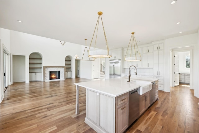 kitchen featuring light countertops, a sink, stainless steel appliances, and light wood finished floors