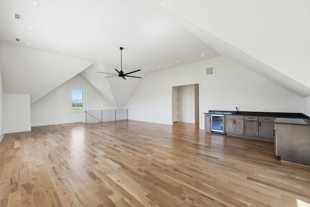 additional living space with light wood-style flooring, wine cooler, lofted ceiling, and visible vents