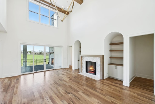 unfurnished living room with light wood finished floors, a fireplace, and a notable chandelier